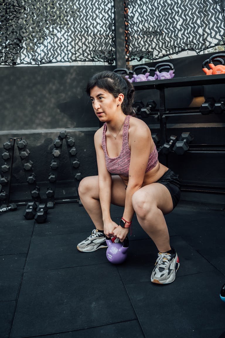 A woman performs a kettlebell squat in a modern Mexico City gym.