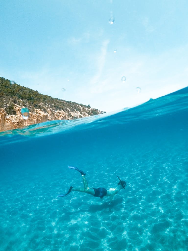 Man snorkeling in the clear blue waters of Sardinia, Italy, enjoying underwater adventure.